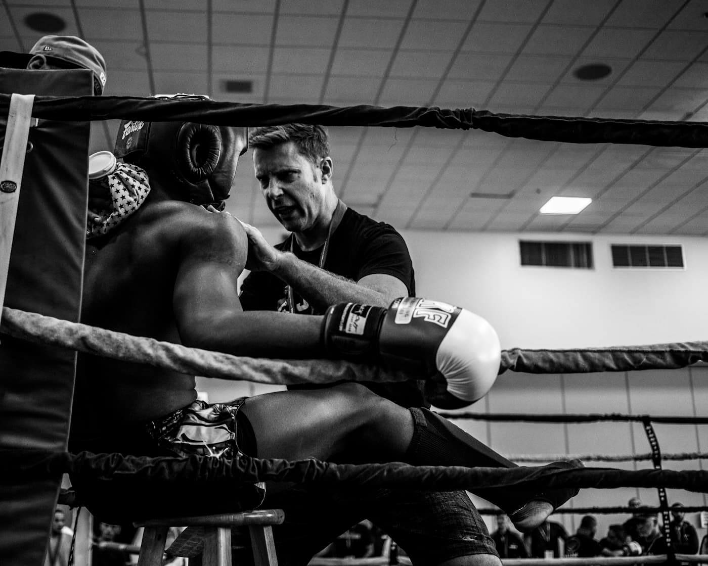 A boxing coach working with a boxer in the ring